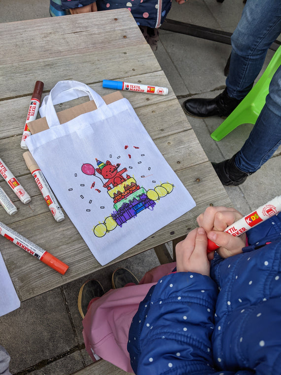 Kinder malen Stofftaschen beim Kindergeburtstag aus